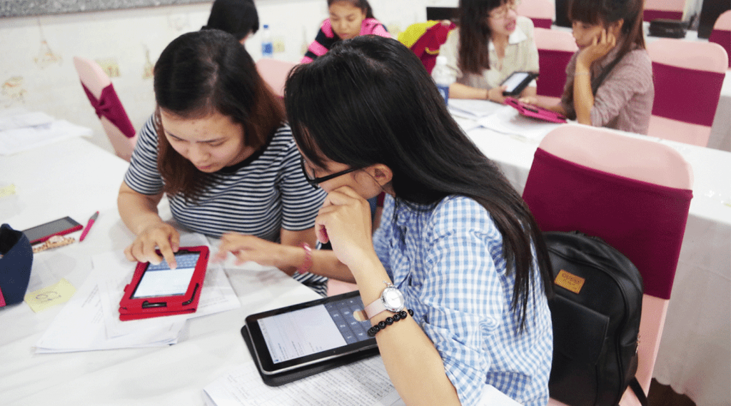 Two women looking down at tablets placed on a table