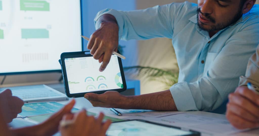 Man holds a tablet showcasing data for collaborators.