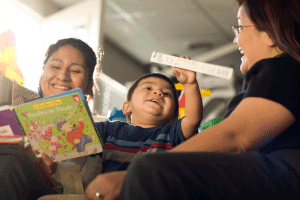 Two women read a story to a little boy.