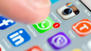 A finger hovers over WhatsApp, with an icon showing one new message, on a smartphone screen.