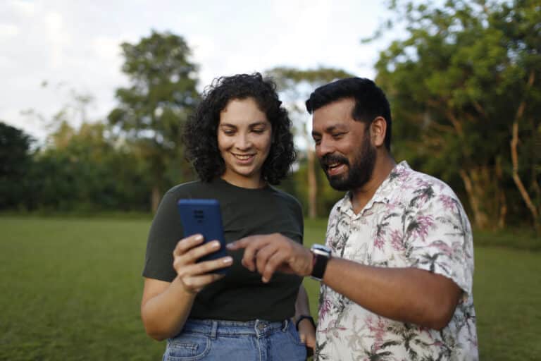 A man and woman look at a device during mobile data collection.